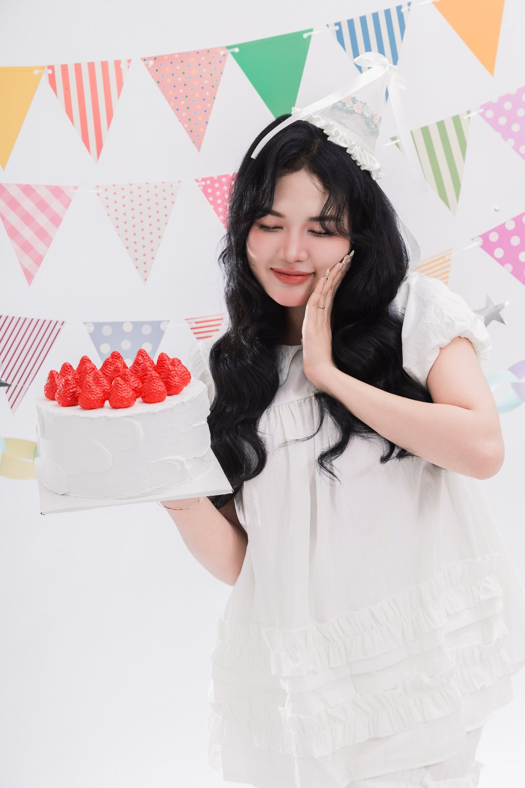 Cận cảnh cô gái nhắm mắt cười cạnh bánh kem