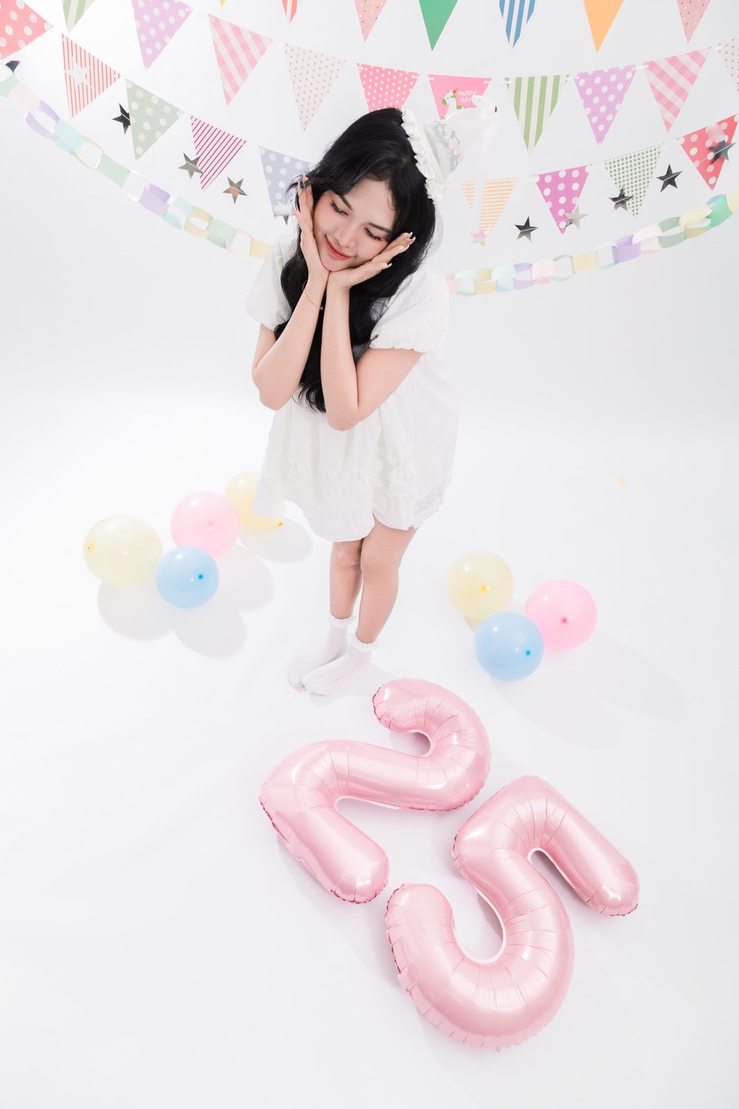 Cô gái tay ôm má, bóng bay số 25 dưới sàn